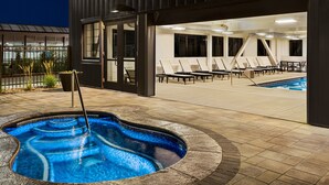 Uma área de piscina ao ar livre com espreguiçadeiras e uma banheira de hidromassagem.