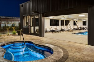 An outdoor swimming pool area with lounge chairs and a hot tub.