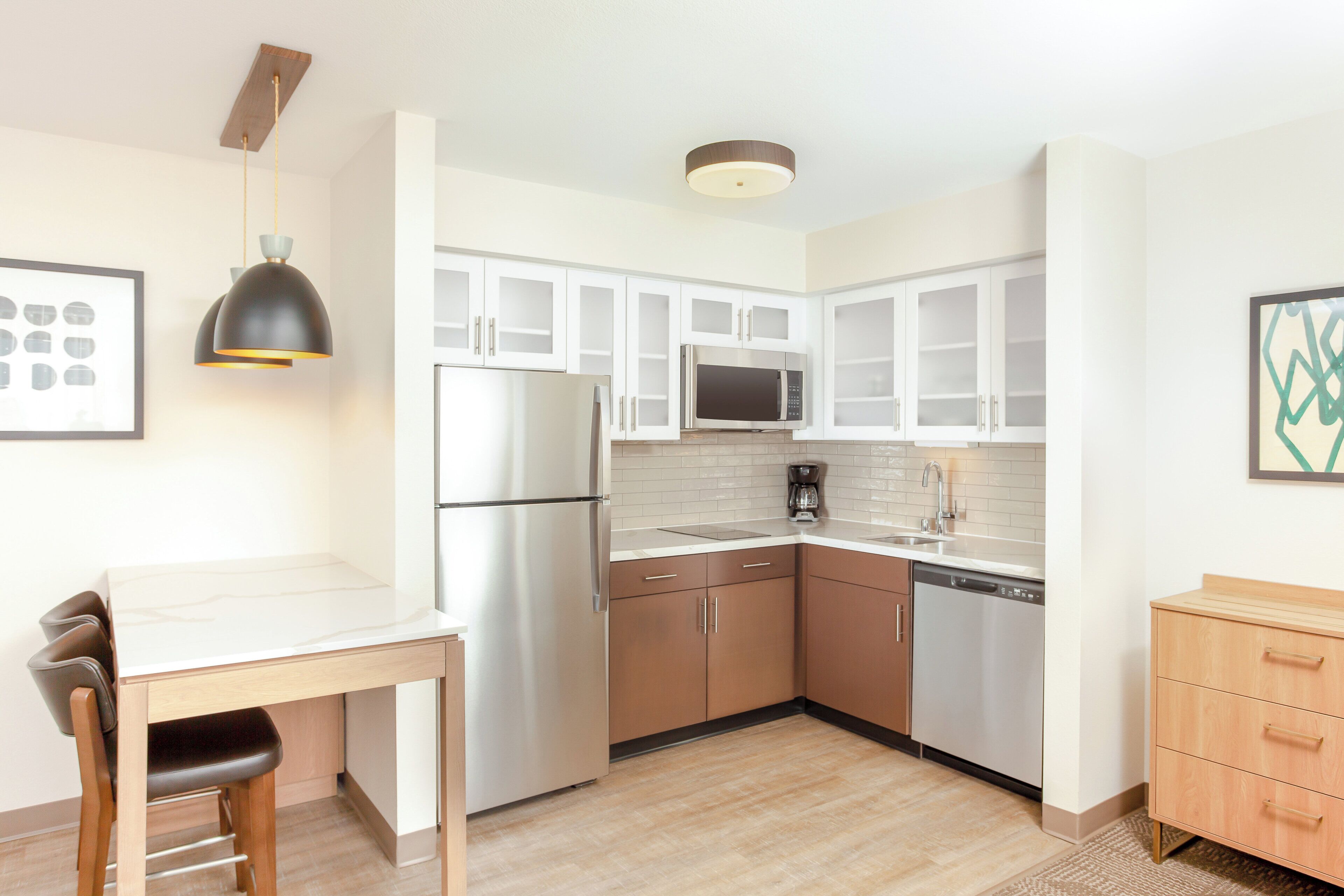 Una cocina moderna con electrodomésticos de acero inoxidable, armarios blancos y una mesa de comedor de madera.