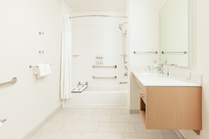 A modern bathroom with a bathtub, a shower, a vanity with a mirror, and a toilet.