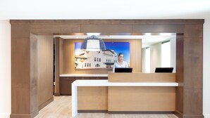 Un mostrador de recepción con diseño moderno, una amplia pantalla digital y una vista de un edificio al fondo.