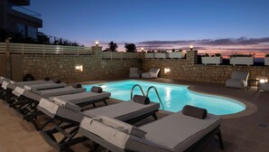 Un espace aménagé au bord de la piscine, avec des chaises longues et un mur en pierre.