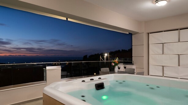 Un bain à remous intérieur moderne avec vue sur l’océan au crépuscule.