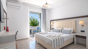 Una habitación de hotel moderna con una cama grande, un escritorio y un balcón con vistas a zonas verdes.