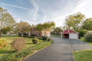 A residential property with a brick house, a red garage, and a well-maintained lawn. - ROOMY!, pet friendly, fenced backyard. (Cleveland)