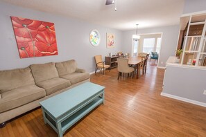 A living room with a beige sofa, a light blue coffee table, and a dining area with a wooden table and chairs. - ROOMY!, pet friendly, fenced backyard. (Cleveland)