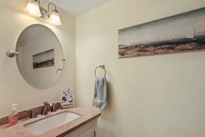A bathroom with a large oval mirror, a sink, and a towel ring.