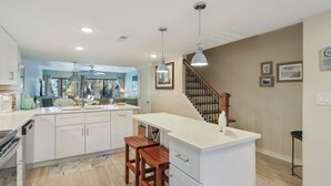 Una cocina moderna con armarios blancos, un banco de madera y una isla central.