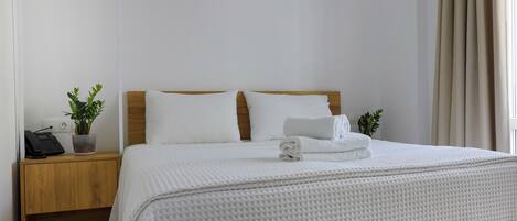 A neatly made bed with white bedding, a wooden headboard, and two bedside lamps.
