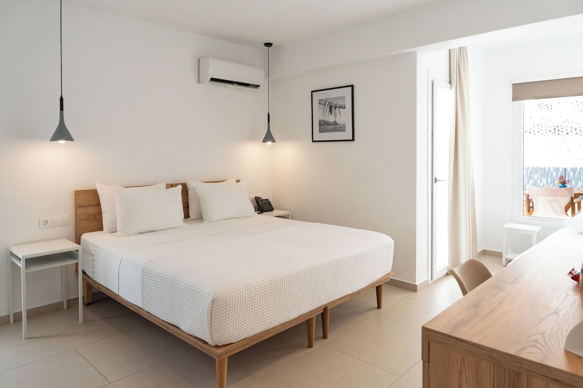 A modern bedroom with a wooden bed, white bedding, a bedside table, and a hanging light fixture.