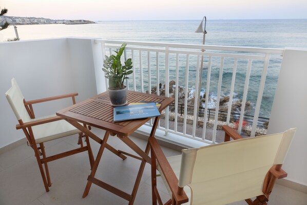 Ein Balkon mit einem Holztisch, Stühlen, einem Blumentopf und einem Buch.