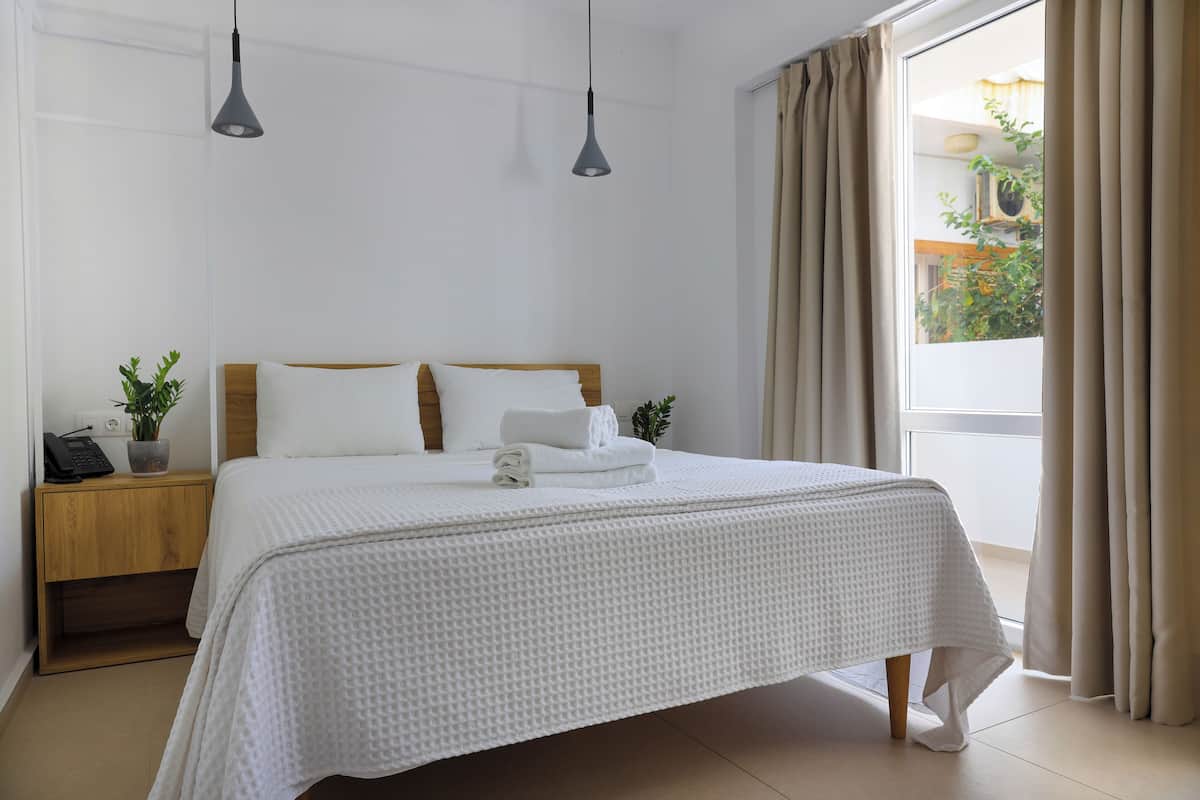 A neatly made bed with a white bedspread, a wooden headboard, and two bedside lamps.