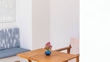 A wooden table and chairs set in a room with a white wall and a patterned cushion.