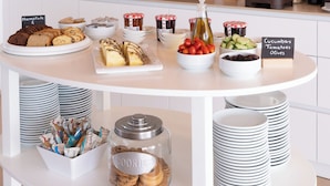 A buffet setup with various food items, including cookies, jams, and condiments, arranged on a white table with hanging wicker lights. - Sea Breeze Hotel (Hersonissos)