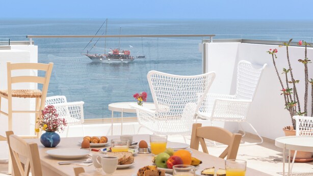 A dining table set with breakfast items and a view of the sea. - Sea Breeze Hotel (Hersonissos)