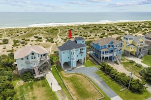 A coastal residential area with houses, a beach, and a lighthouse.