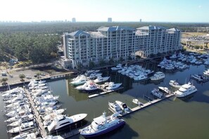 Uma marina com vários iates atracados, um grande edifício de hotel e uma ponte ao fundo.