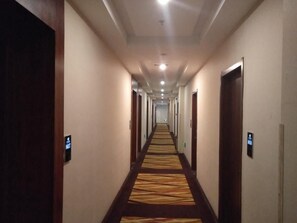 A hotel hallway with carpeted floors, doors on both sides, and a long corridor leading to a bright end. - Greentree Alliance Bengbu Railway Station Hotel (Bengbu)