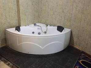 Una bañera grande y blanca, independiente, con un diseño curvo, un grifo y dos pomos negros.