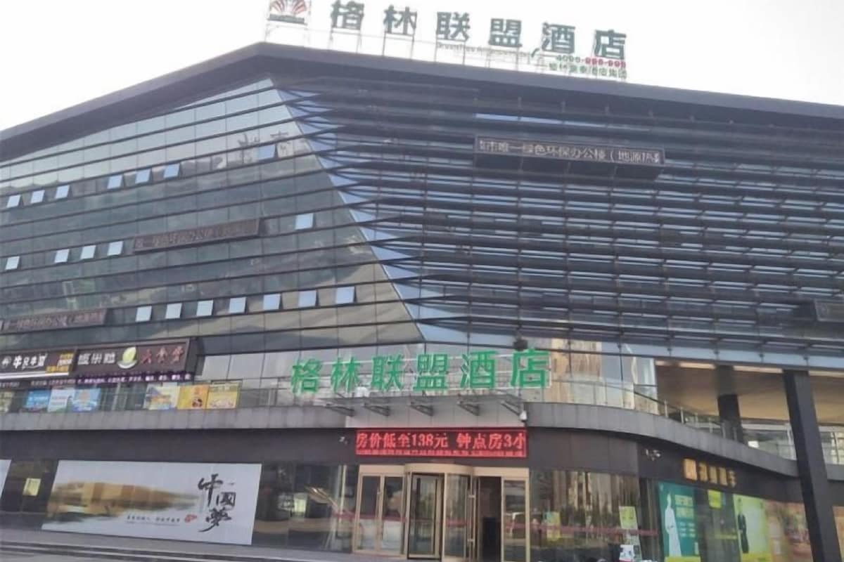 Un hôtel moderne doté d’une façade en verre, d’une enseigne indiquant « Wuxi Union Hotel » et d’une entrée bien visible avec une pancarte rouge indiquant les tarifs des chambres.