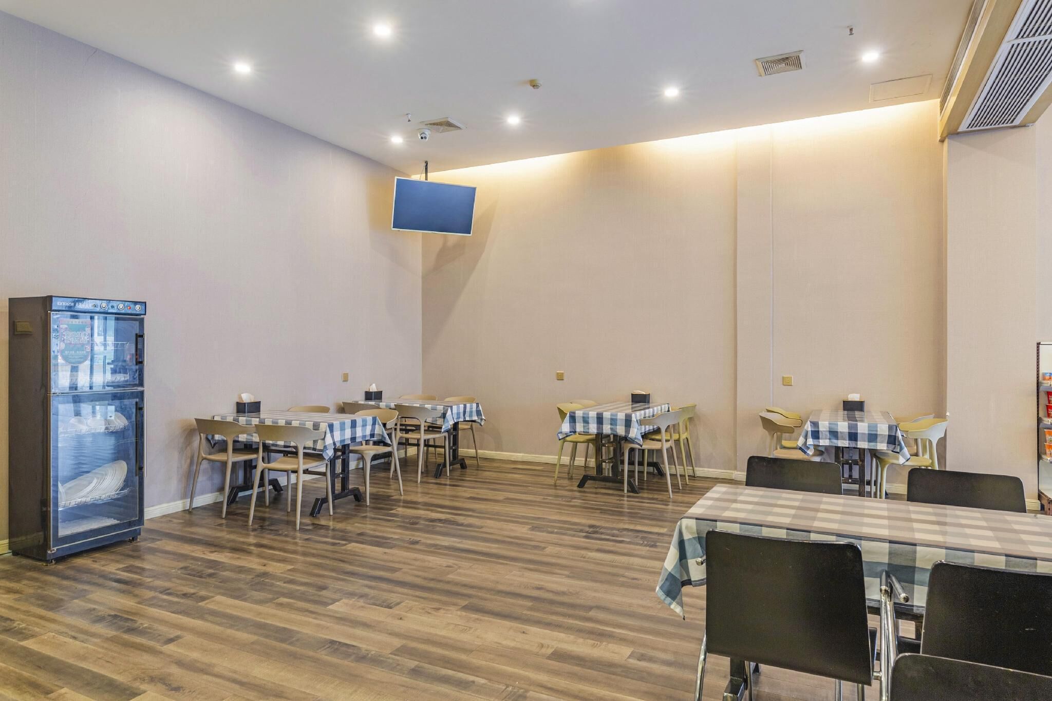 A conference room with tables and chairs, a flat-screen TV, and a refrigerator.