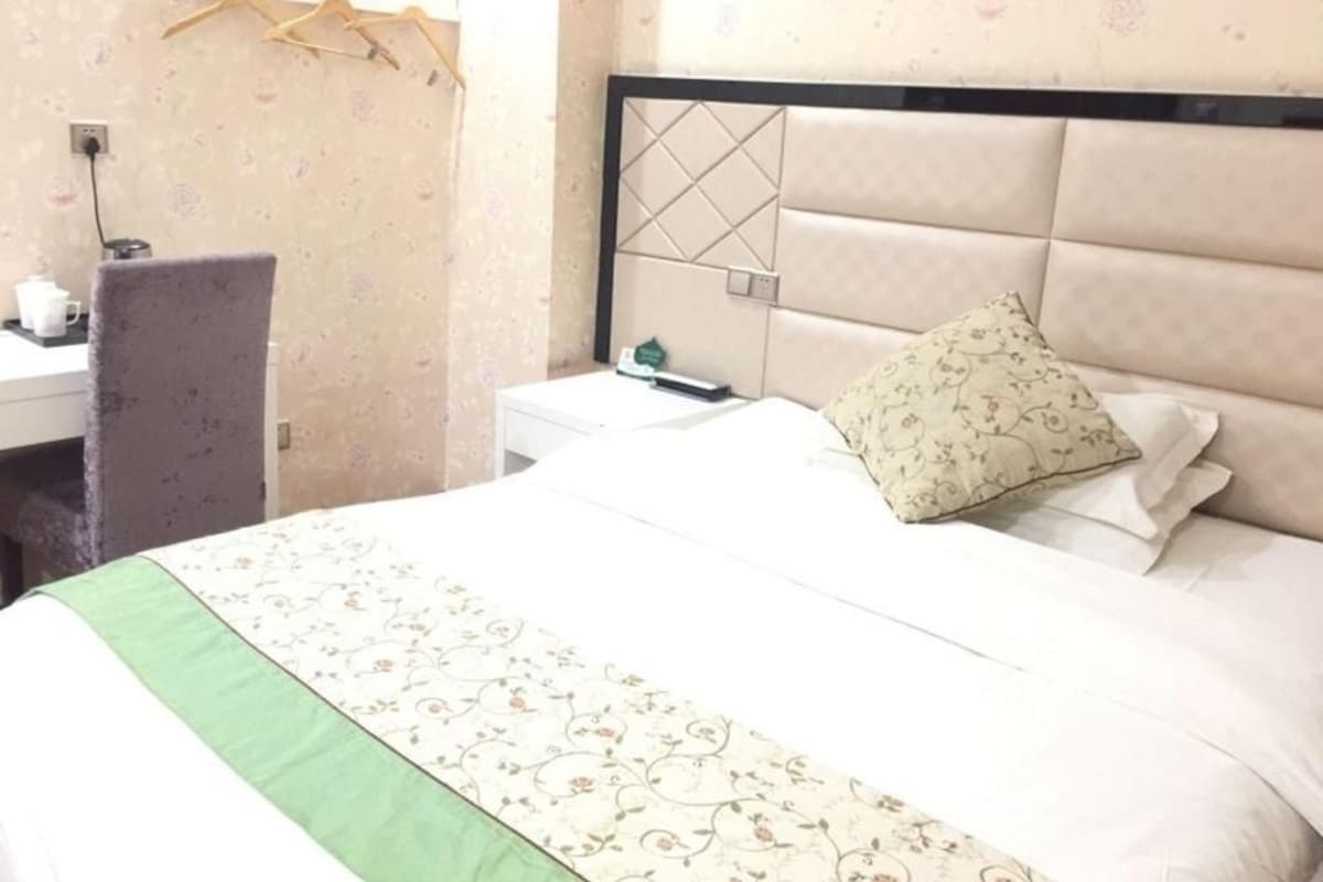 Une chambre d’hôtel avec un lit, une table de chevet, un bureau et une chaise.