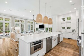 A modern kitchen with white cabinetry, a large island, stainless steel appliances, and pendant lighting. - GORGEOUS WaterColor Beach Home w/ Carriage House, LSV, 10 Bikes! (Santa Rosa Beach)