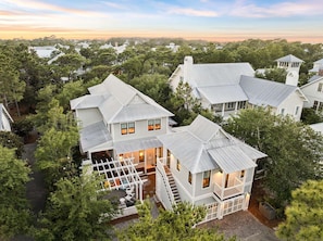 A large, multi-story house with a prominent front porch and a staircase leading to the upper floor. - GORGEOUS WaterColor Beach Home w/ Carriage House, LSV, 10 Bikes! (Santa Rosa Beach)
