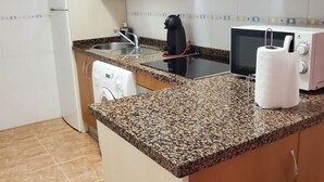 A compact kitchen with a granite countertop, a microwave, a toaster, and a dish drying rack.