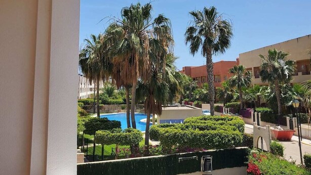 A resort with a pool, palm trees, and a clear blue sky.