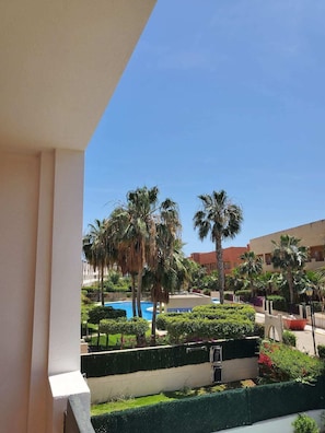 A resort with a pool, palm trees, and a clear blue sky.
