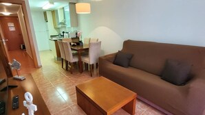 A living room with a brown sofa, a wooden coffee table, and a dining area with a table and chairs.