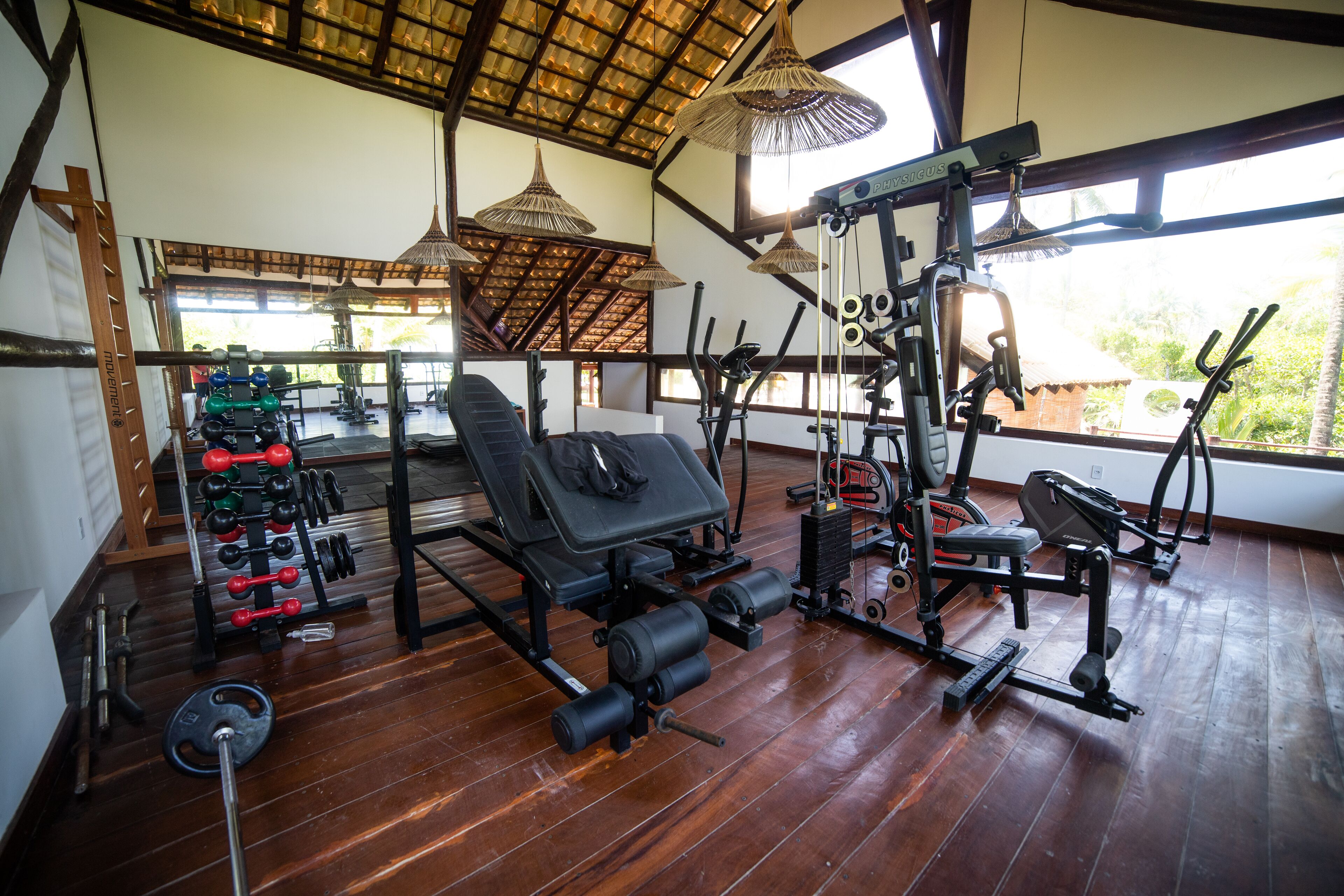 A gym with various exercise equipment, a bench, and a rack of weights.