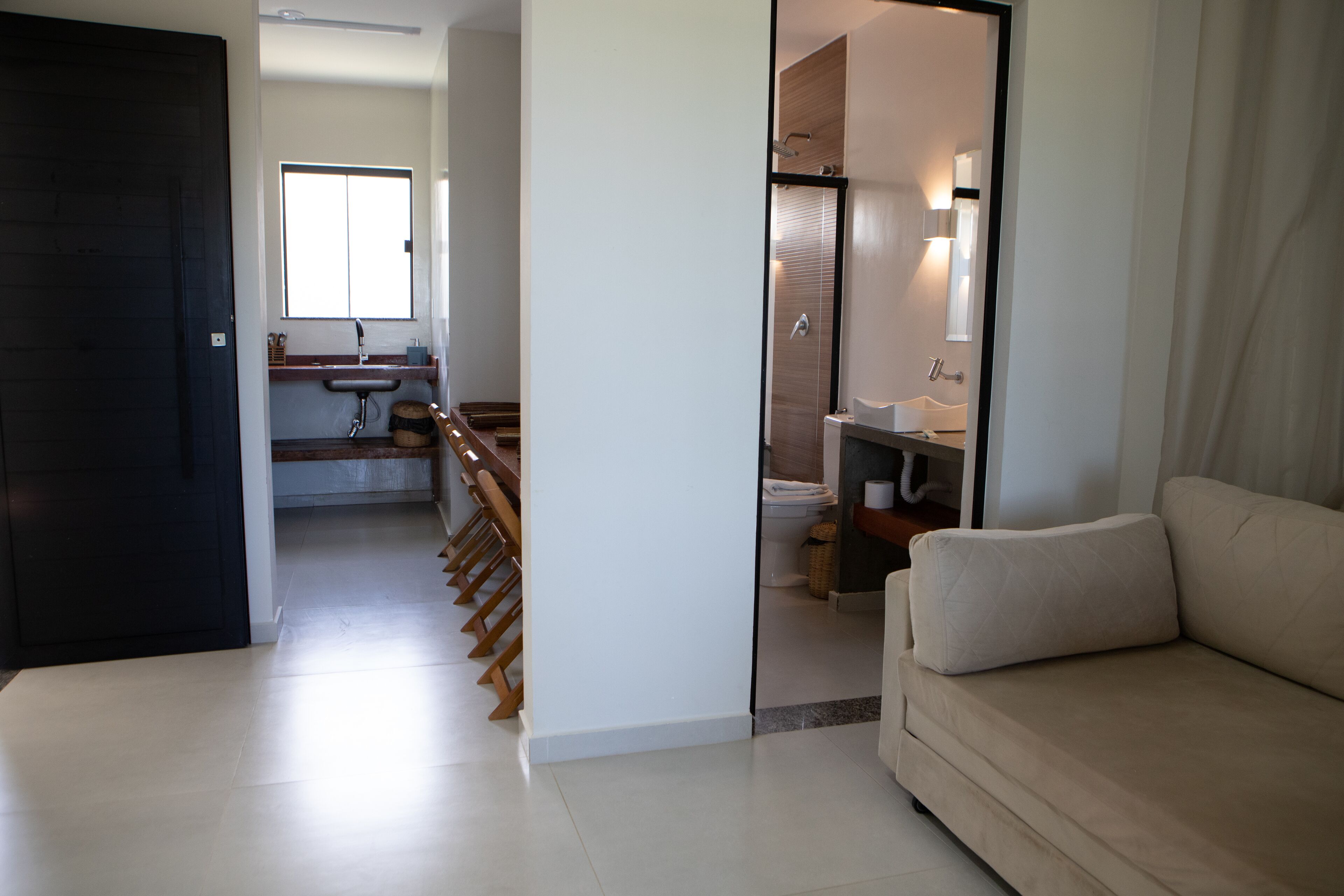 A modern living room with a sofa, a staircase leading to a bathroom, and a kitchen area.