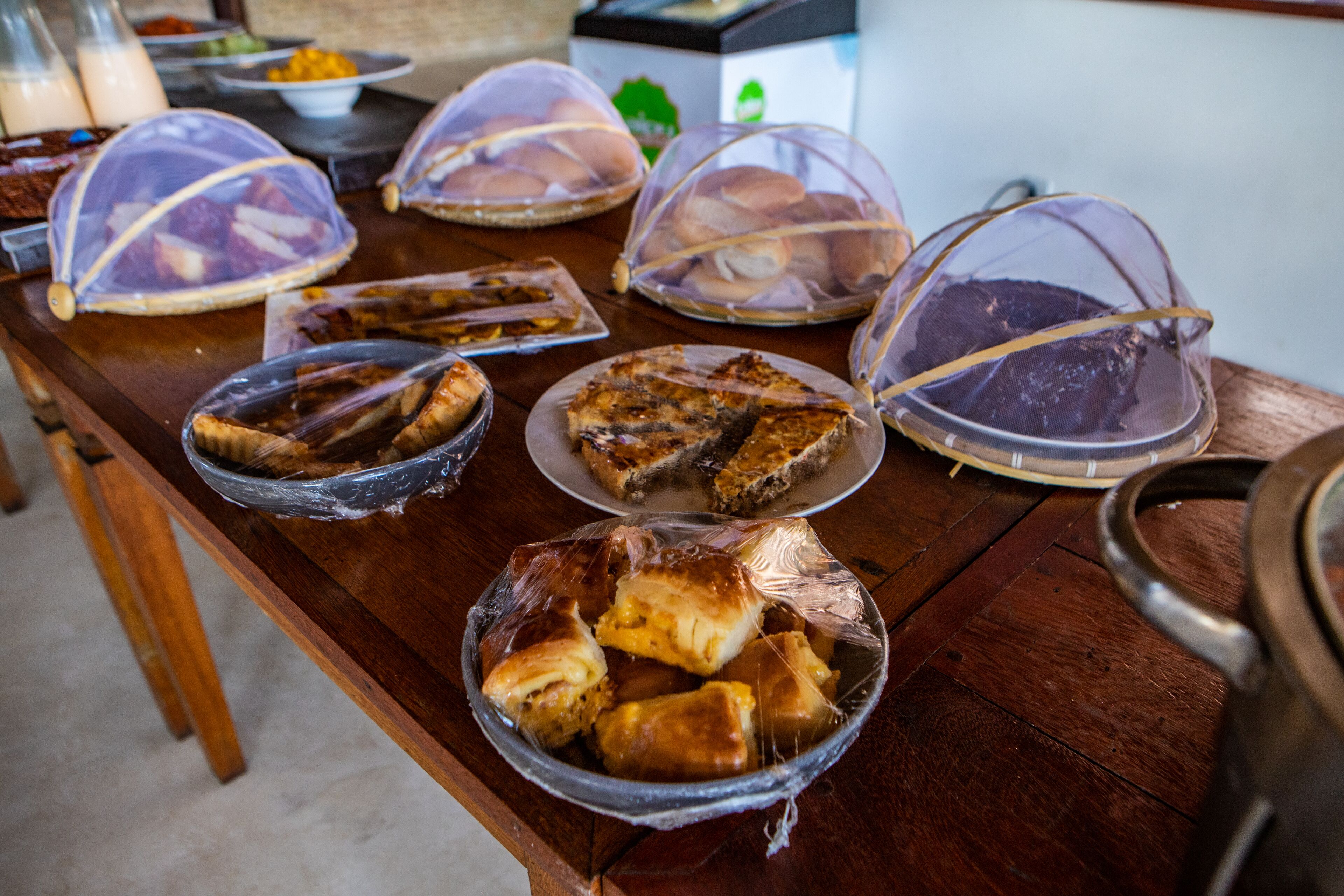A buffet table with various covered dishes, including pies and pastries.
