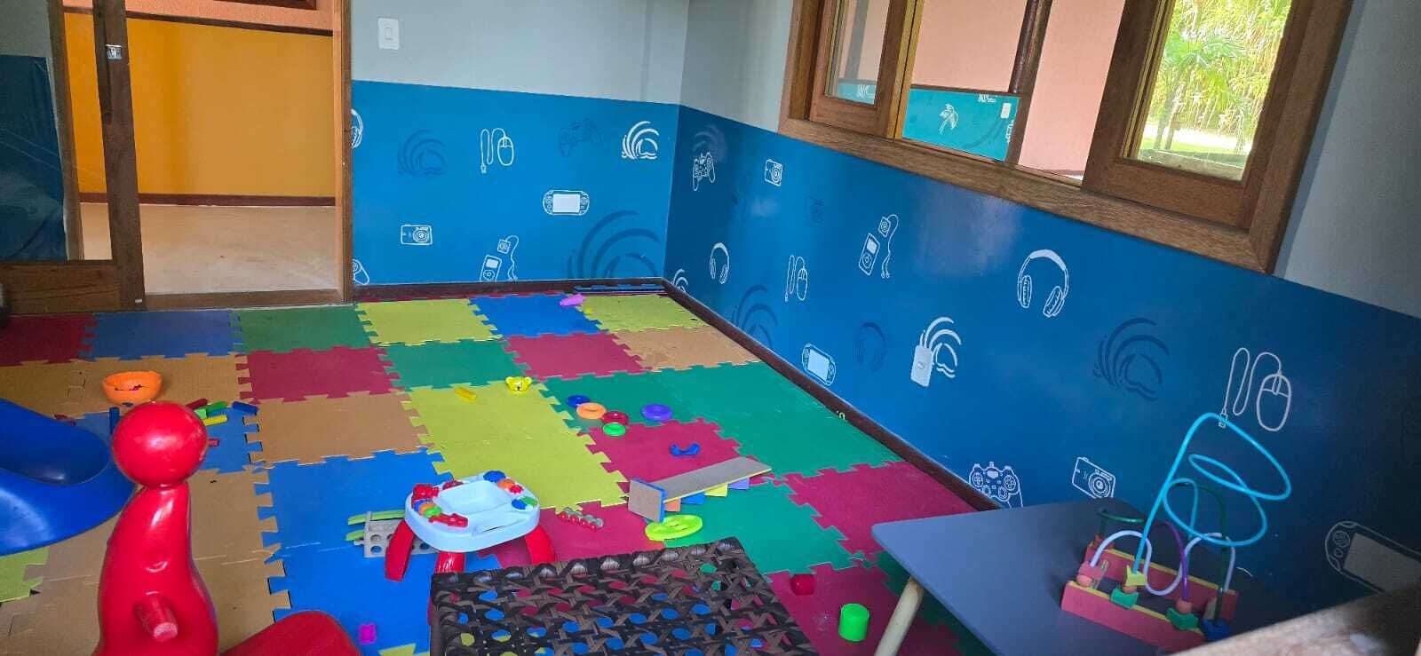 A playroom with colorful foam mats, toys, and a wall decorated with white icons of various electronic devices.