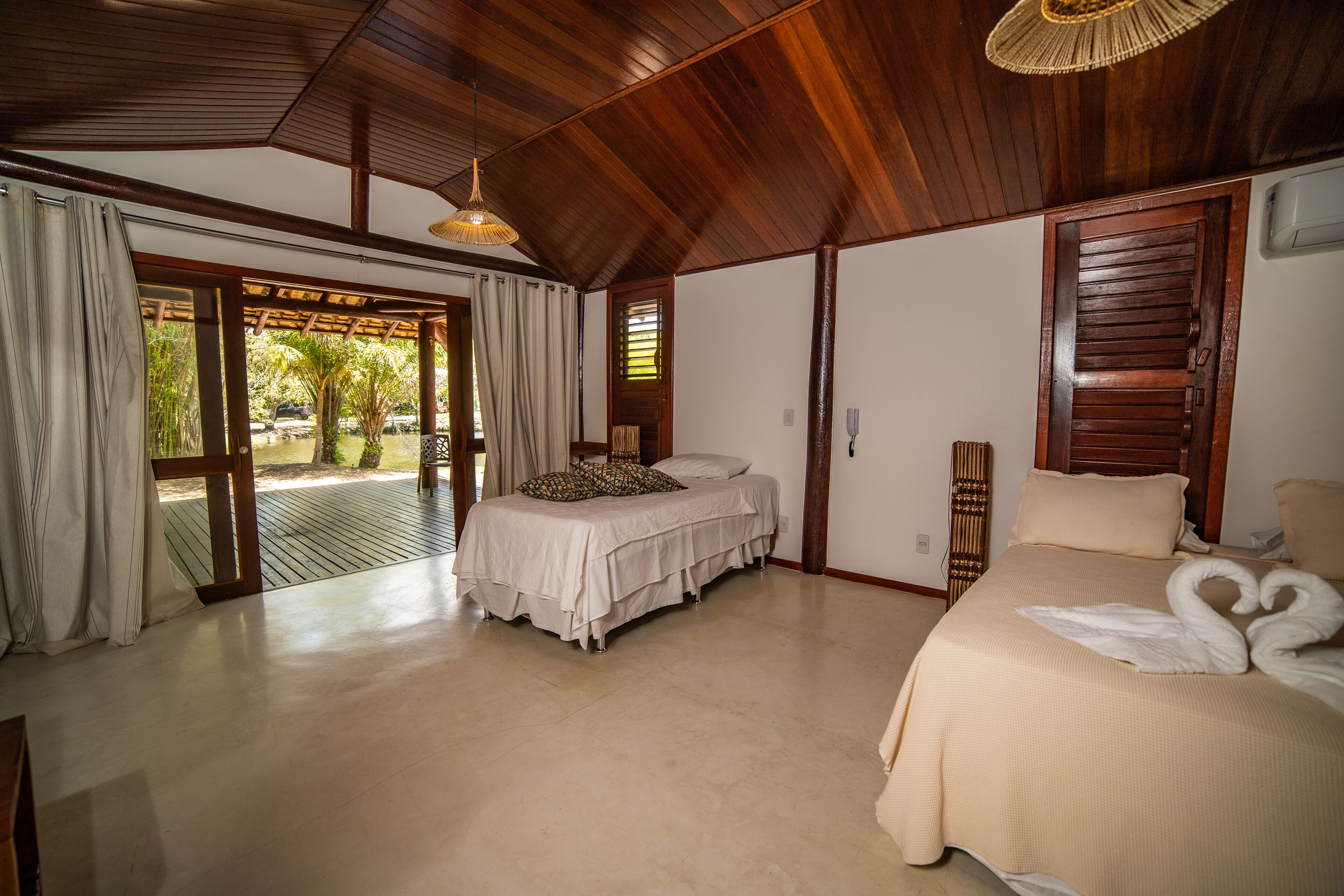 A spacious bedroom with a large bed, a smaller bed, and a view through a glass door to an outdoor area.