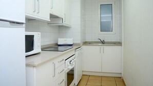 Una cocina pequeña con armarios blancos, un microondas, un tostador y un lavabo.