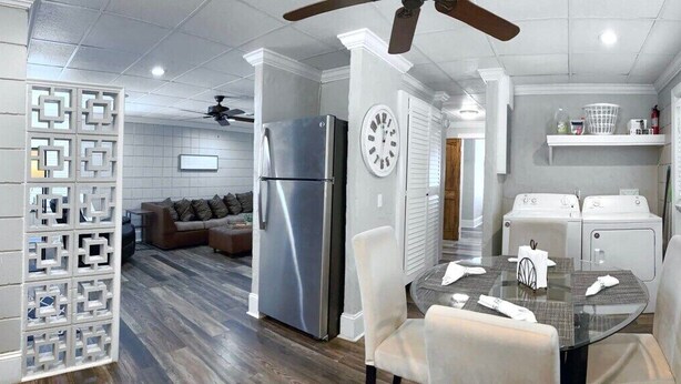 Una cocina moderna con refrigerador, estufa y lavadoras. Cuenta con una mesa de comedor con sillas y un ventilador de techo.