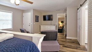A bedroom with a bed, a desk, a chair, a TV, and a wardrobe. - The Cottage House - Family Friendly, Close to GSU! (Statesboro)