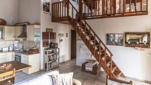 Amplia sala de estar con escalera de madera, cocina equipada con electrodomésticos modernos y un rincón de estar acogedor.