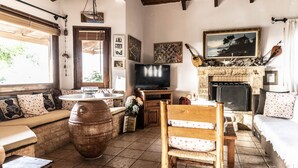 Una sala de estar acogedora con un barril de madera, un televisor, una chimenea y varias fotografías enmarcadas en las paredes.