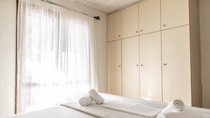 Una habitación de hotel con una cama, un armario espacioso y una ventana con cortinas traslúcidas.