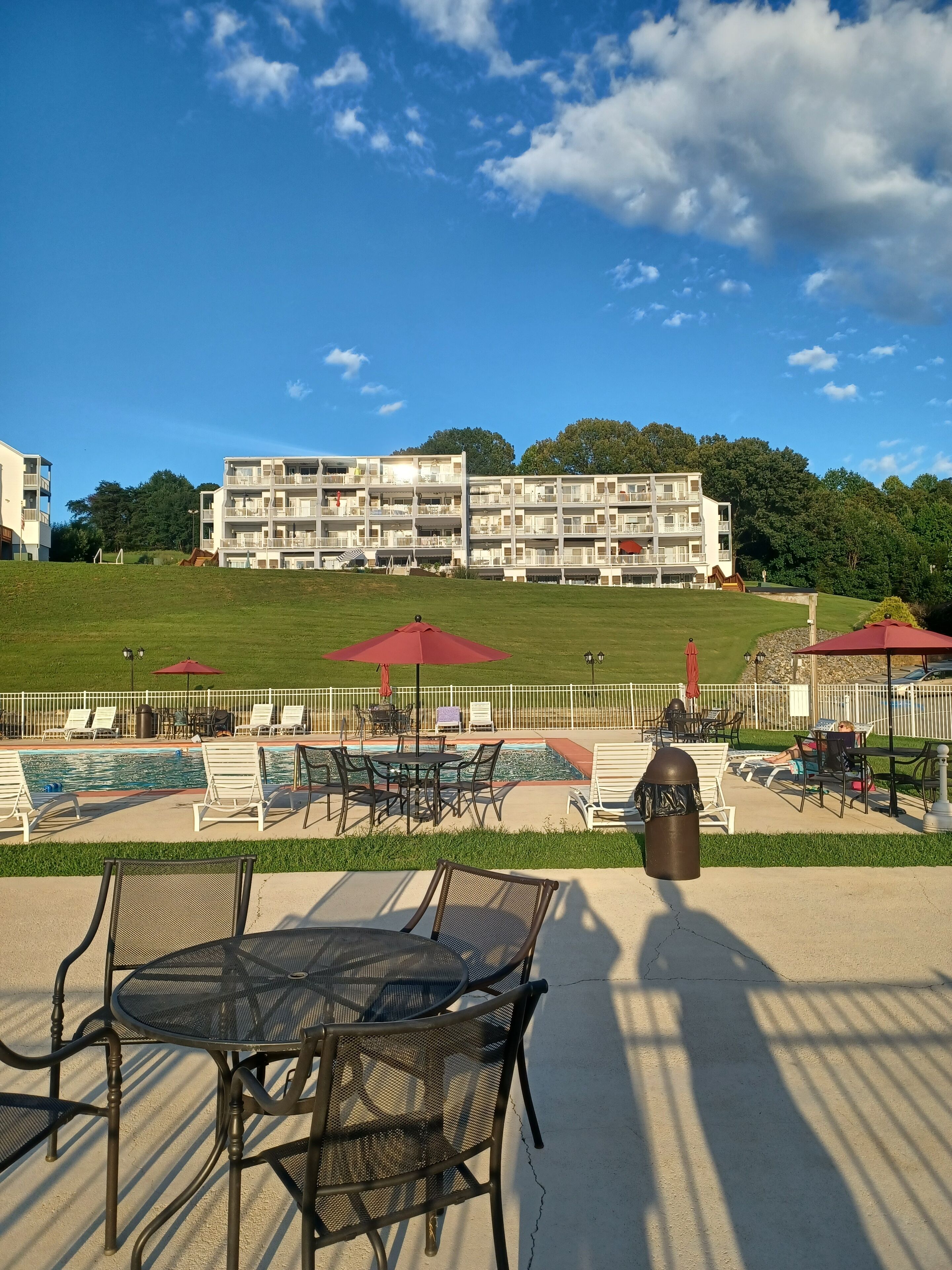A poolside area with lounge chairs, umbrellas, and a view of a multi-story building.