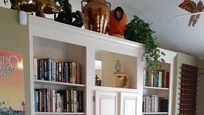 Un salon chaleureux avec une bibliothèque remplie de livres, un fauteuil à bascule et une table basse.