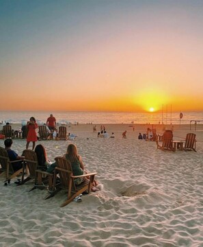 A beach with wooden chairs and people relaxing. - BestHomeStay-Parede Beach (Lisbon) (Parede)
