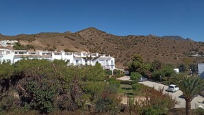 A coastal residential area with white buildings, a clear blue sky, and a mountainous backdrop. - Refurbished Villa With Private Garden And Large Terraces (Nerja)