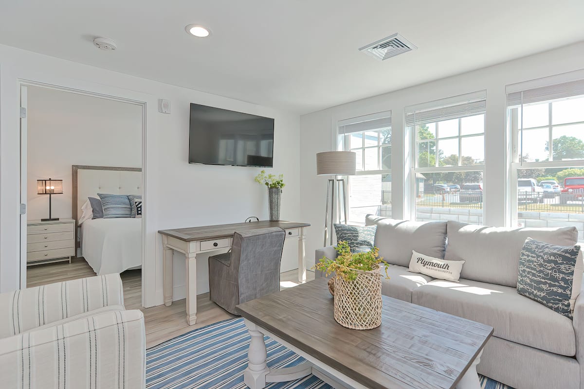 A modern living room with a sofa, coffee table, and a flat-screen TV mounted on the wall.