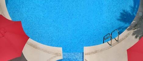 A circular pool with a clear blue water surface, surrounded by a decorative pool edge and a small pool ladder.