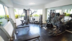 A gym with various exercise equipment, including a bench, weight machines, and cardio machines. - Adhara Express (Cancun)